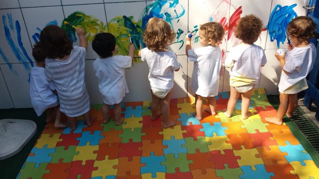 Crianças pintando na parede em atividade no Atelier de Artes