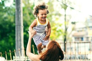 Uma mulher levanta uma criança feliz para o alto