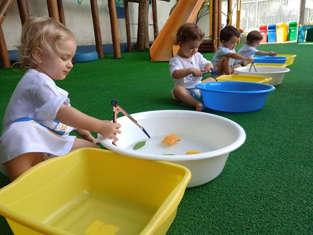 Crianças brincando com água e bacias coloridas no parque da DreamKids